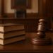 A gavel and law books on a desk in a courtroom setting