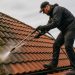 A roofer removing moss from roof tiles with specialist equipment